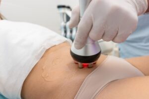 A person is using an electric device to treat the abdomen.